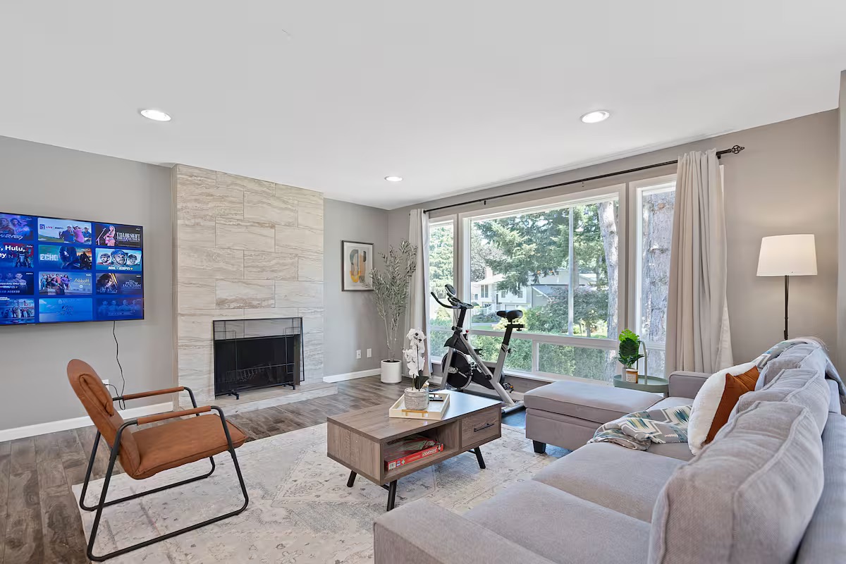 A bright Kirkland living room with a gray sofa, leather chair and fireplace.