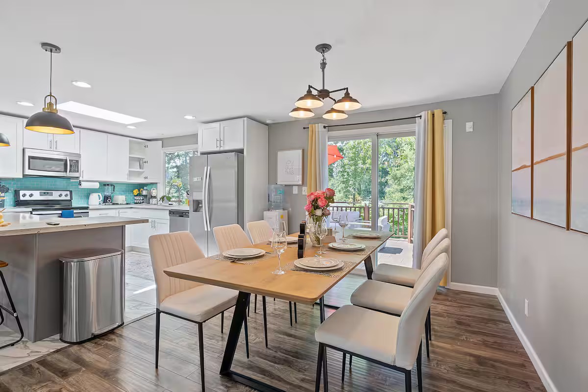 A six-seat dining area alongside a white kitchen and breakfast bar.